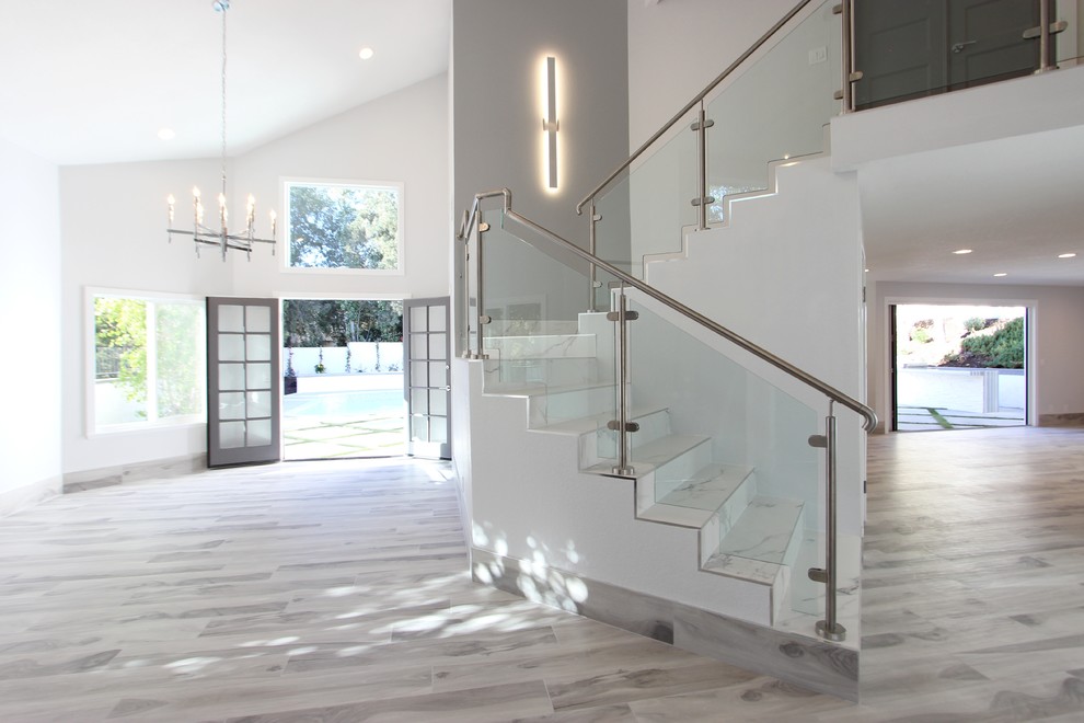 На фото: п-образная лестница в современном стиле с ступенями из плитки, подступенками из плитки и стеклянными перилами