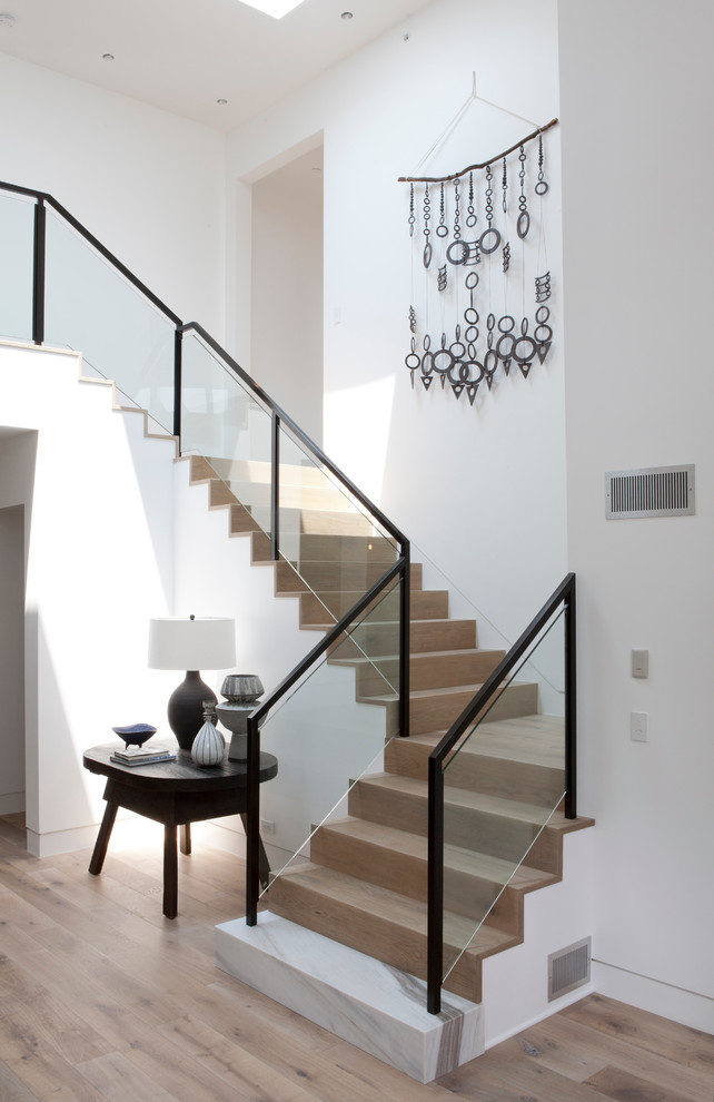 Photo of a large nautical wood glass railing staircase in Los Angeles with wood risers and feature lighting.