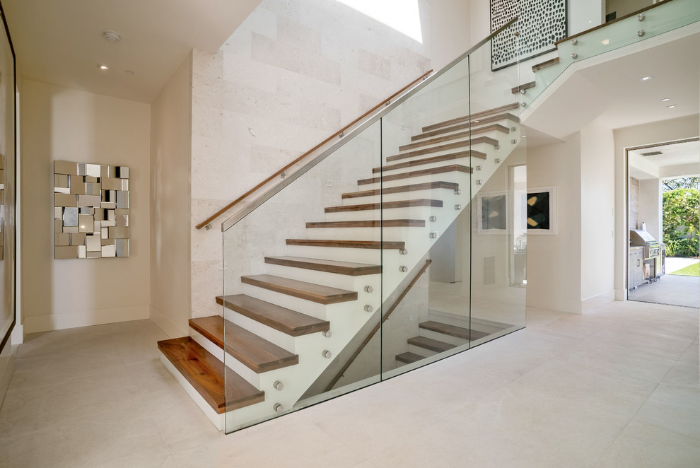 Diseño de escalera en L actual grande con escalones de madera, contrahuellas de madera pintada y barandilla de vidrio