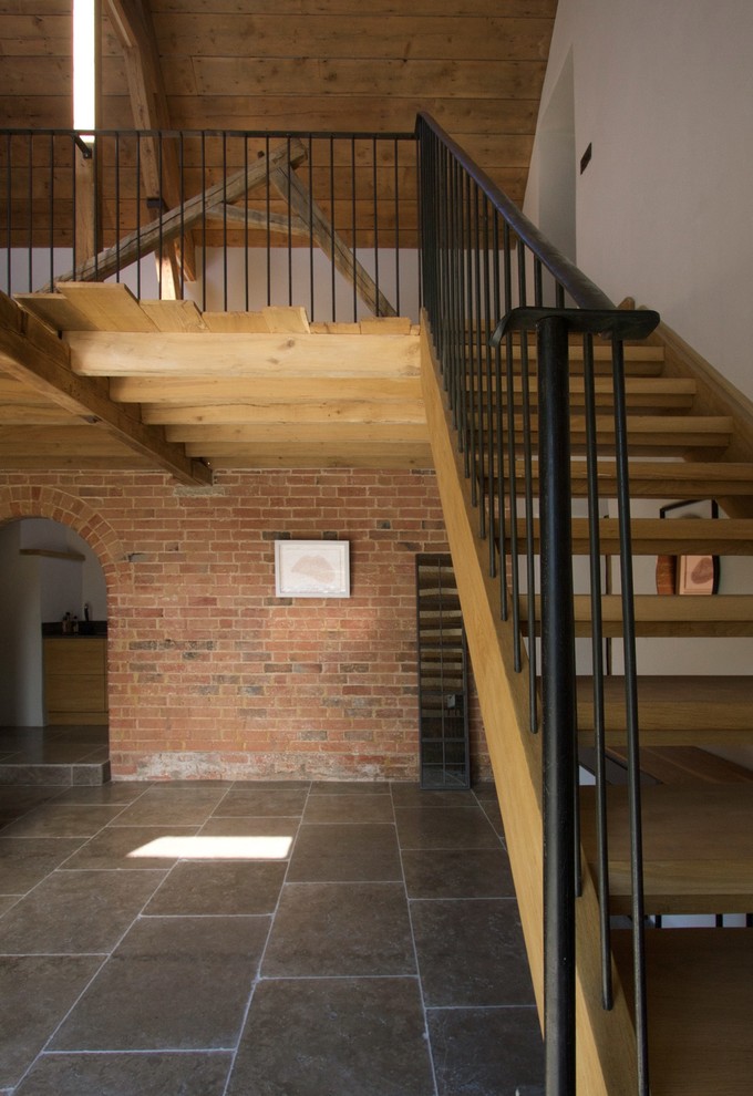 Cette image montre un escalier sans contremarche rustique en L de taille moyenne avec des marches en bois et un garde-corps en métal.