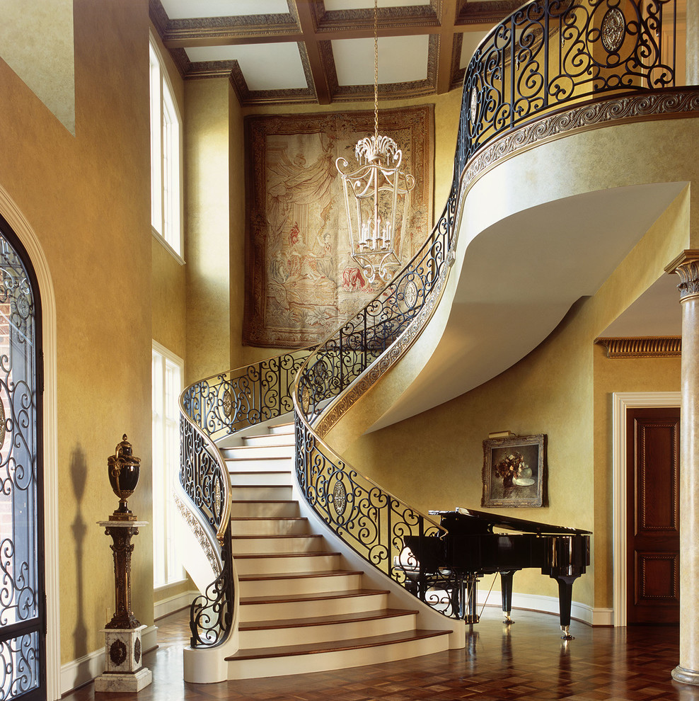 На фото: большая изогнутая лестница в викторианском стиле с деревянными ступенями, крашенными деревянными подступенками и металлическими перилами
