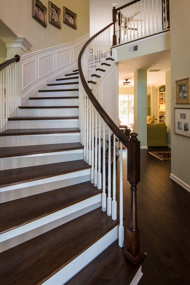 Стильный дизайн: большая изогнутая деревянная лестница в классическом стиле с деревянными ступенями - последний тренд
