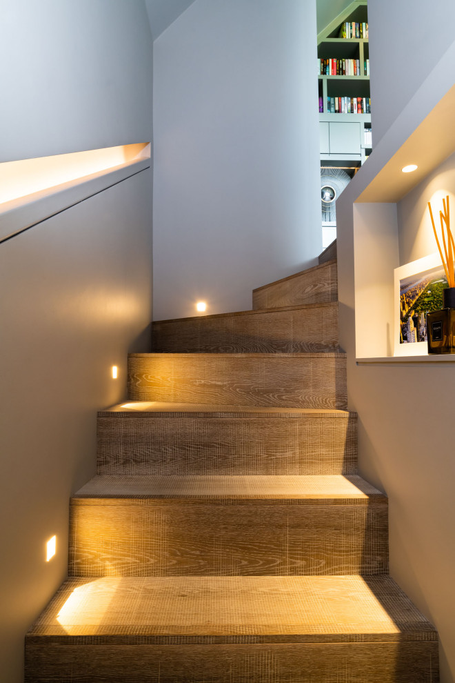 Réalisation d'un très grand escalier courbe design avec des marches en bois et des contremarches en bois.