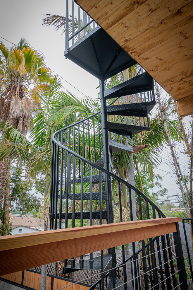 Cette image montre un petit escalier hélicoïdal minimaliste avec des marches en métal et un garde-corps en métal.