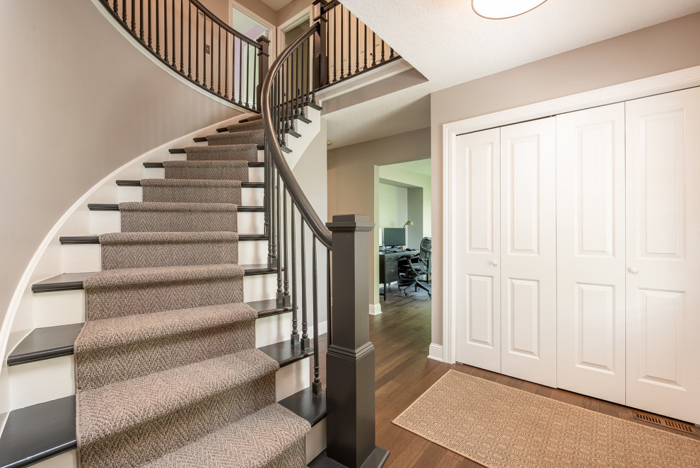 Стильный дизайн: винтовая деревянная лестница с ступенями с ковровым покрытием и деревянными перилами - последний тренд