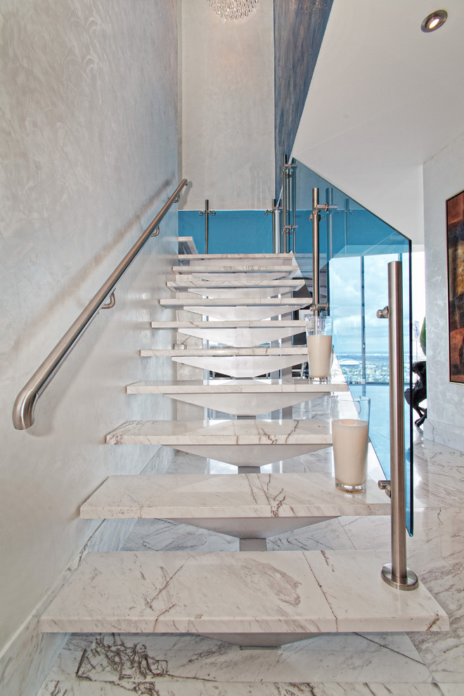 На фото: лестница на больцах, среднего размера в современном стиле с мраморными ступенями и стеклянными перилами без подступенок с