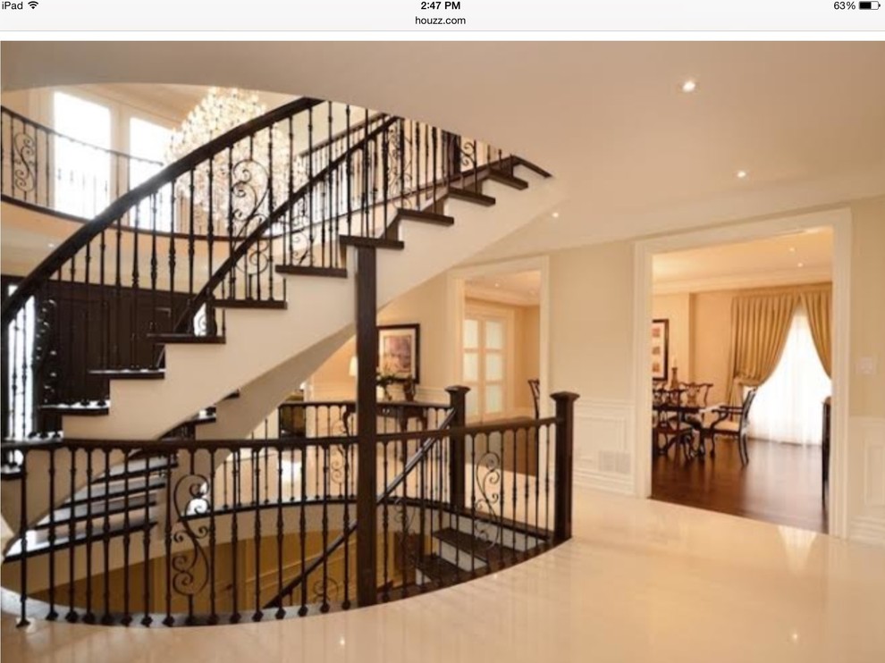 Diseño de escalera curva clásica grande con escalones de madera, contrahuellas de metal y barandilla de metal