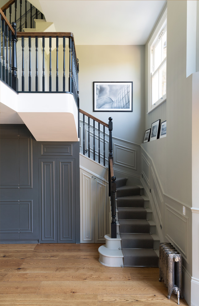 На фото: изогнутая лестница в викторианском стиле с крашенными деревянными ступенями и крашенными деревянными подступенками с
