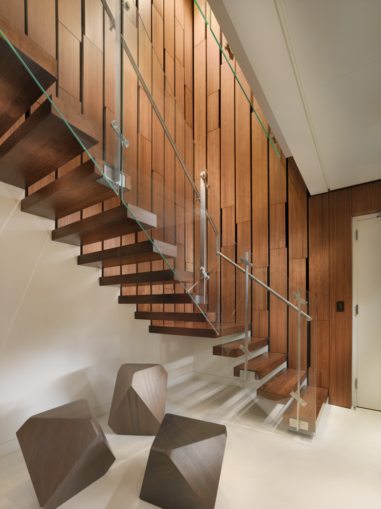 На фото: большая угловая лестница в современном стиле с деревянными ступенями и стеклянными перилами без подступенок