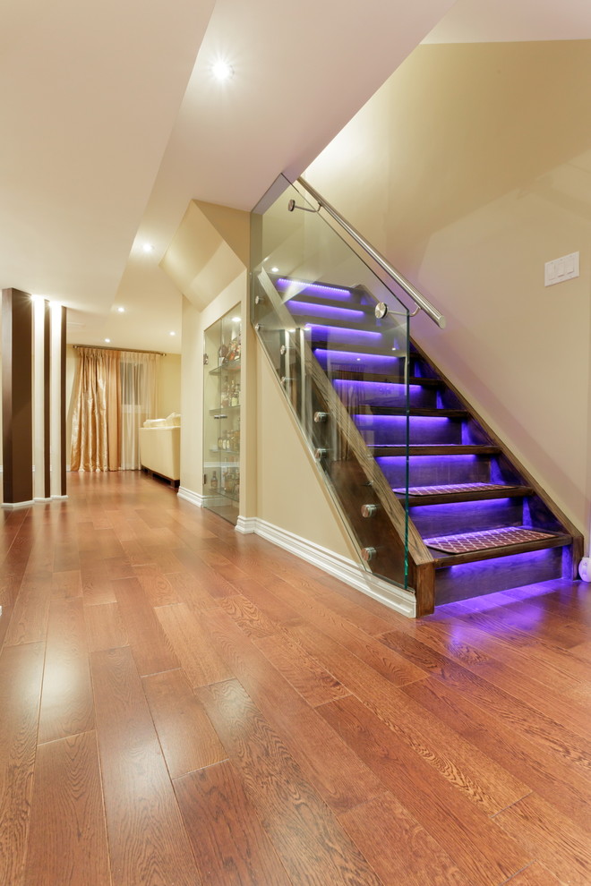 Foto de escalera recta minimalista de tamaño medio con barandilla de vidrio, escalones de madera y contrahuellas de madera