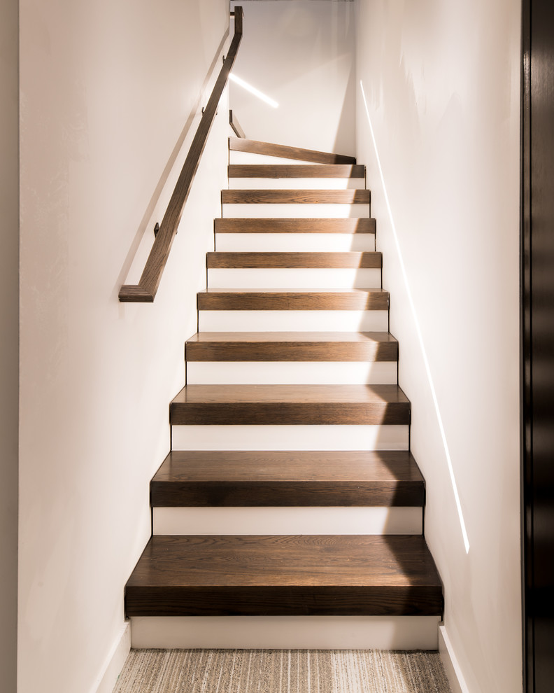 На фото: угловая лестница среднего размера в стиле модернизм с деревянными ступенями, крашенными деревянными подступенками и деревянными перилами с