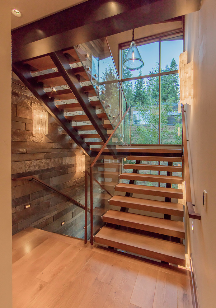 Aménagement d'un grand escalier sans contremarche montagne en U avec des marches en bois et un garde-corps en verre.