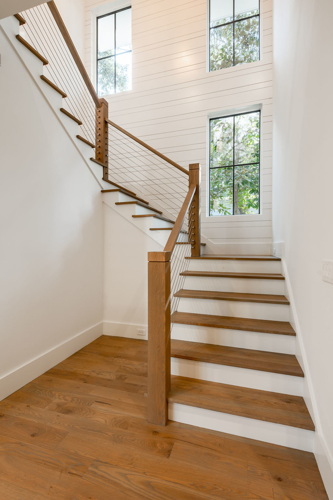 Photo of a medium sized beach style wood l-shaped wire cable railing staircase in Charleston with painted wood risers.