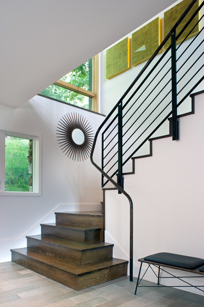 Cette image montre un escalier design en L de taille moyenne avec des marches en bois, des contremarches en bois et un garde-corps en métal.