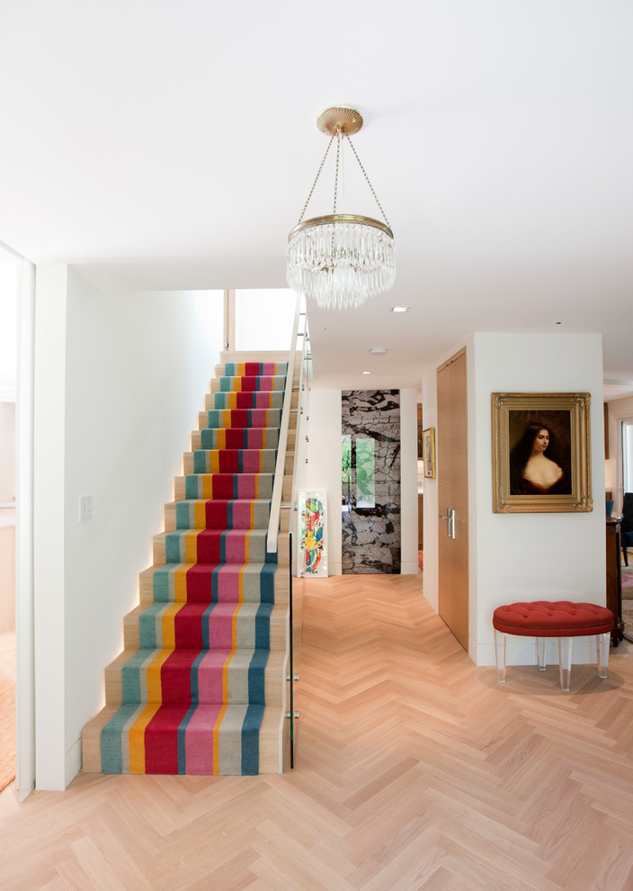 Imagen de escalera recta ecléctica con escalones de madera, contrahuellas de madera y barandilla de vidrio