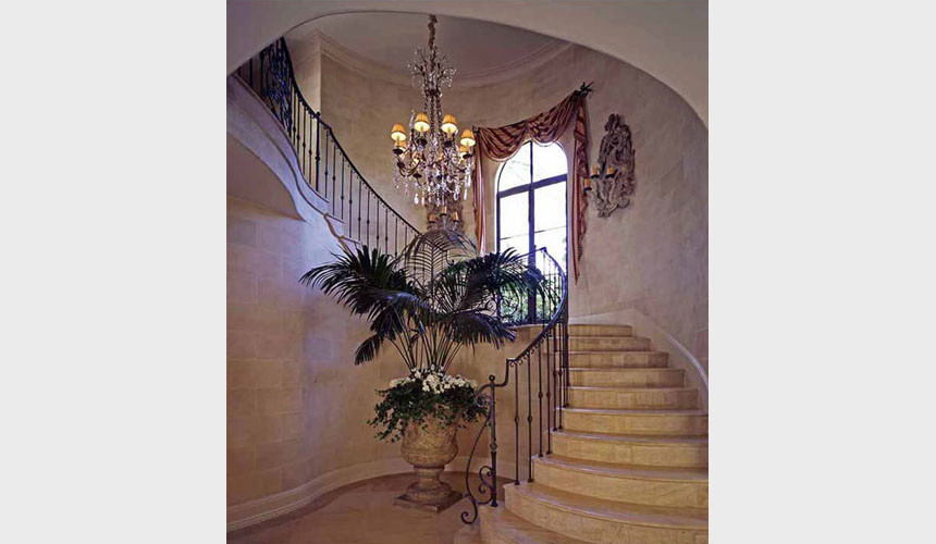 Modelo de escalera curva mediterránea de tamaño medio con escalones con baldosas, contrahuellas con baldosas y/o azulejos y barandilla de metal