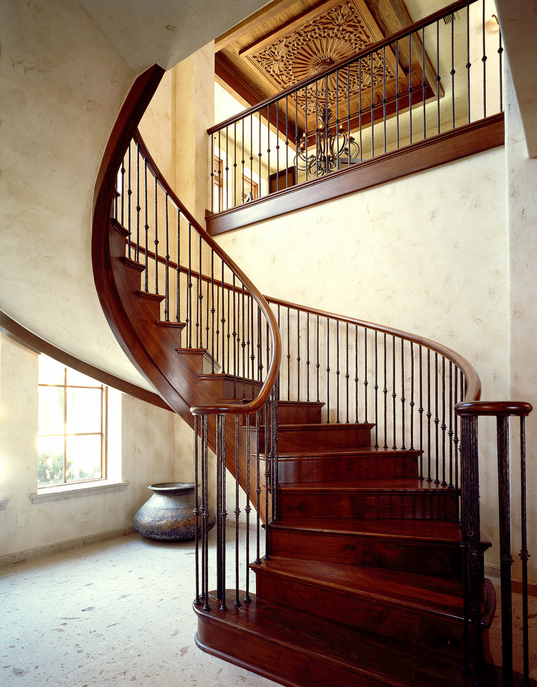 Ejemplo de escalera curva mediterránea con escalones de madera y contrahuellas de madera
