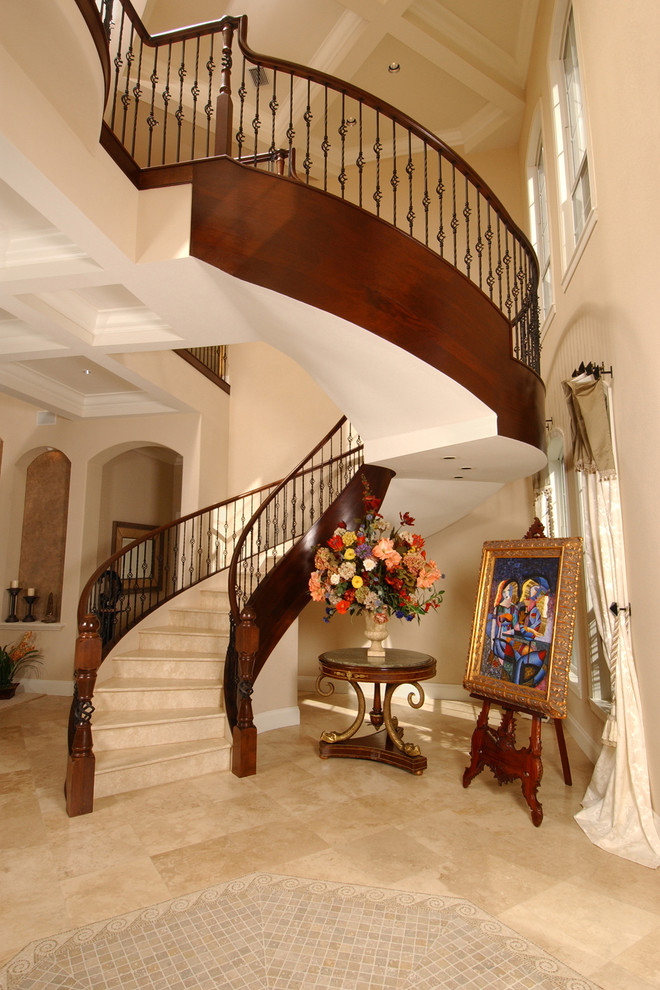 На фото: изогнутая лестница в средиземноморском стиле с ступенями из травертина, подступенками из травертина и металлическими перилами