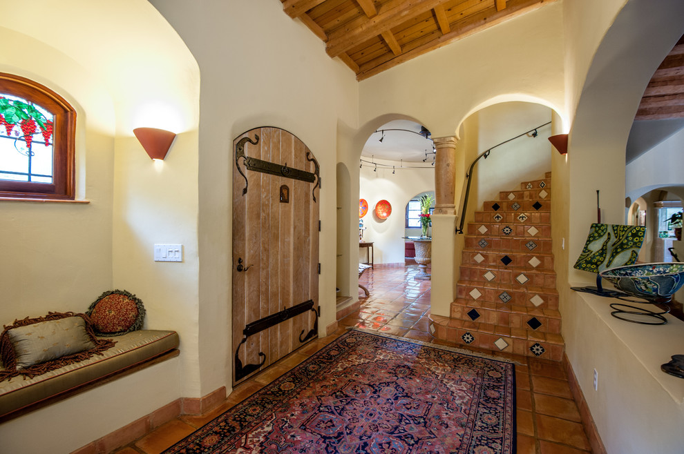 Источник вдохновения для домашнего уюта: изогнутая лестница в средиземноморском стиле с ступенями из терракотовой плитки, подступенками из терракотовой плитки и металлическими перилами