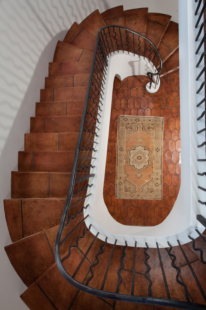Staircase - mediterranean terra-cotta metal railing staircase idea in Other