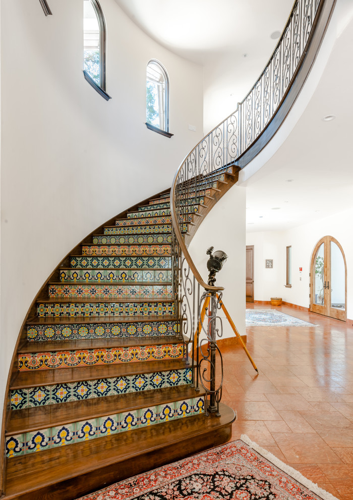На фото: большая прямая лестница в средиземноморском стиле с деревянными ступенями и подступенками из плитки с