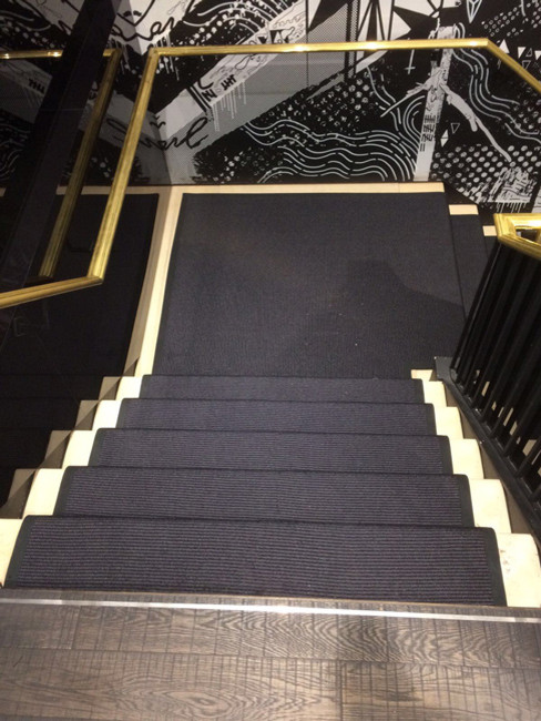 Foto de escalera en L minimalista grande con escalones enmoquetados, contrahuellas enmoquetadas y barandilla de metal
