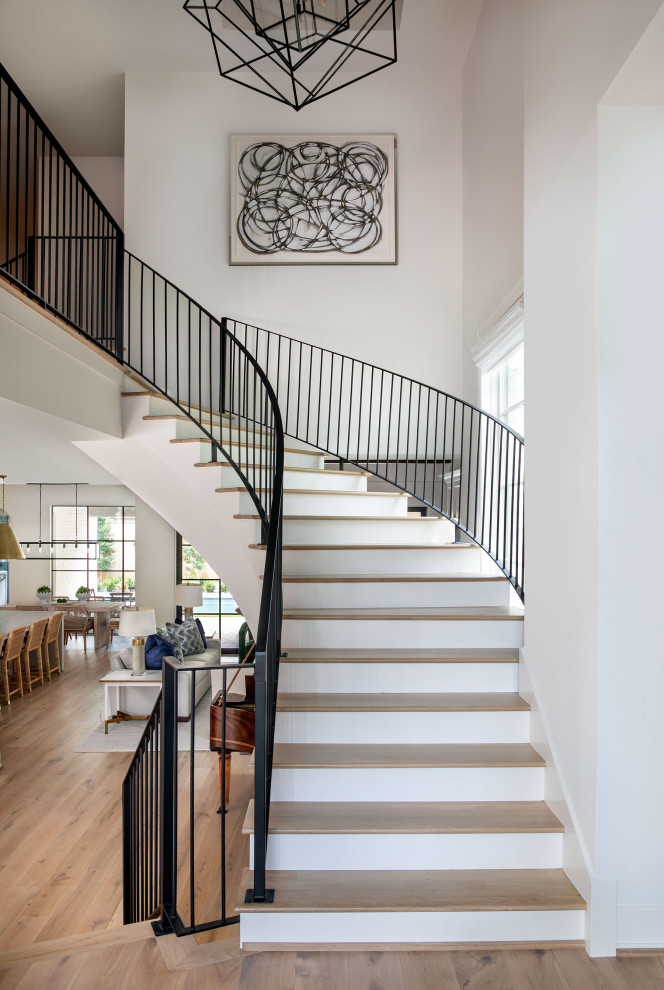 Пример оригинального дизайна: огромная винтовая лестница в современном стиле с деревянными ступенями, крашенными деревянными подступенками и металлическими перилами