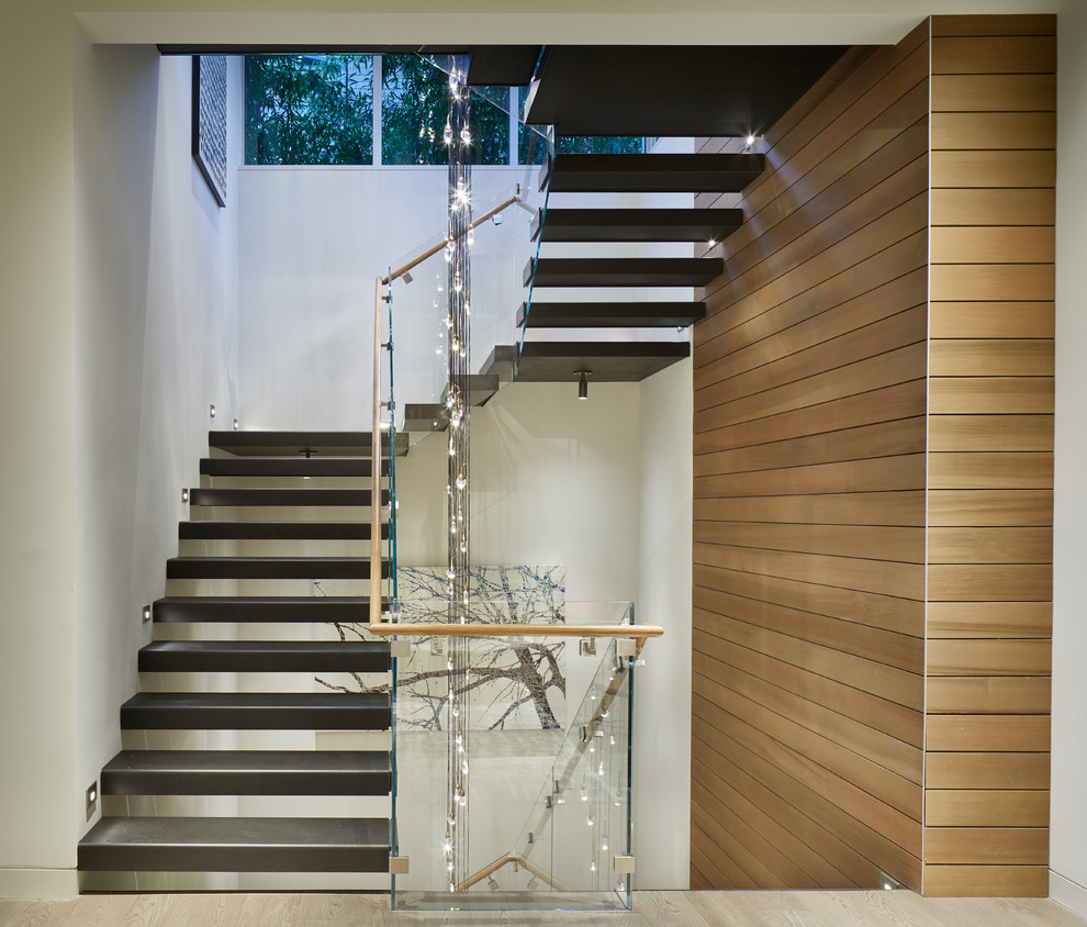 Идея дизайна: огромная лестница на больцах в стиле модернизм с металлическими ступенями и стеклянными перилами без подступенок