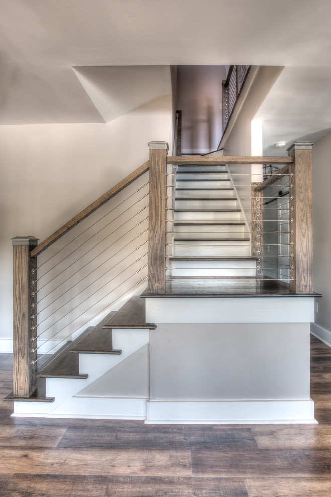Diseño de escalera en L de estilo de casa de campo de tamaño medio con escalones de madera, contrahuellas de madera pintada y barandilla de madera