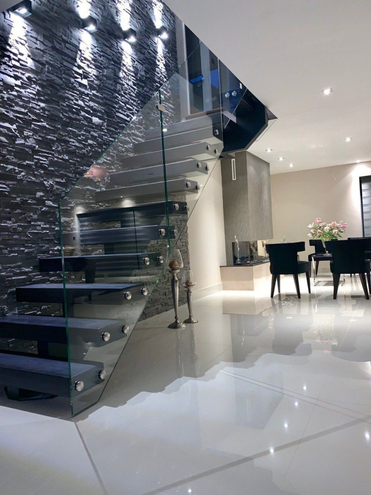 Photo of a medium sized modern wood floating glass railing staircase in Cheshire with metal risers.