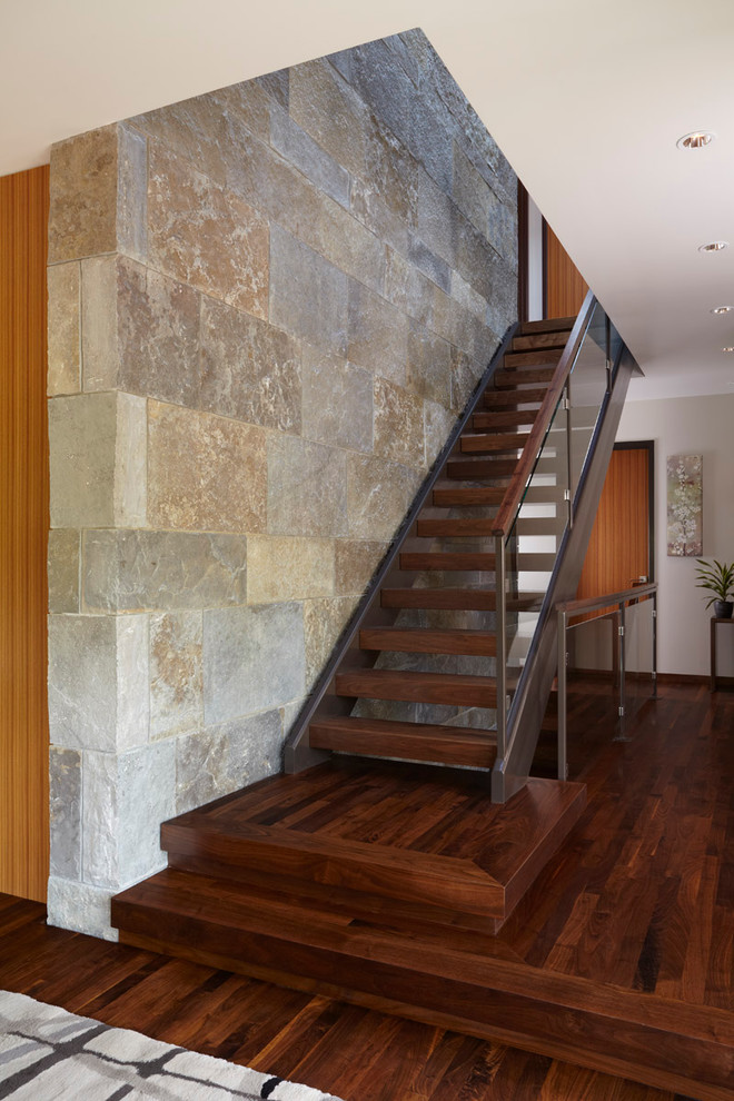 Ejemplo de escalera recta actual sin contrahuella con escalones de madera y barandilla de vidrio