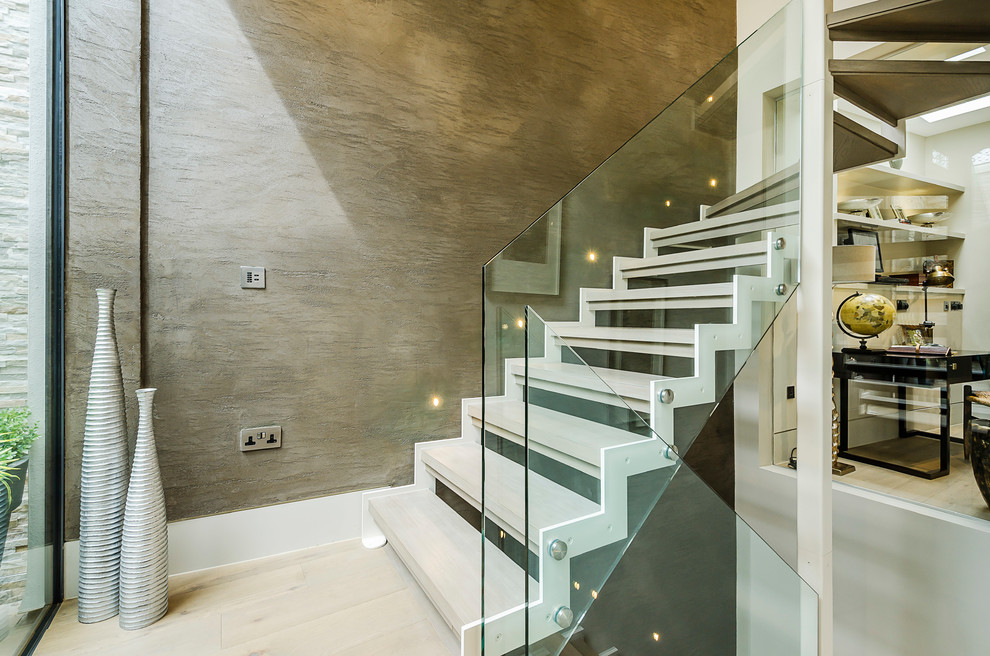 Photo of a contemporary wood u-shaped glass railing staircase in London with open risers.