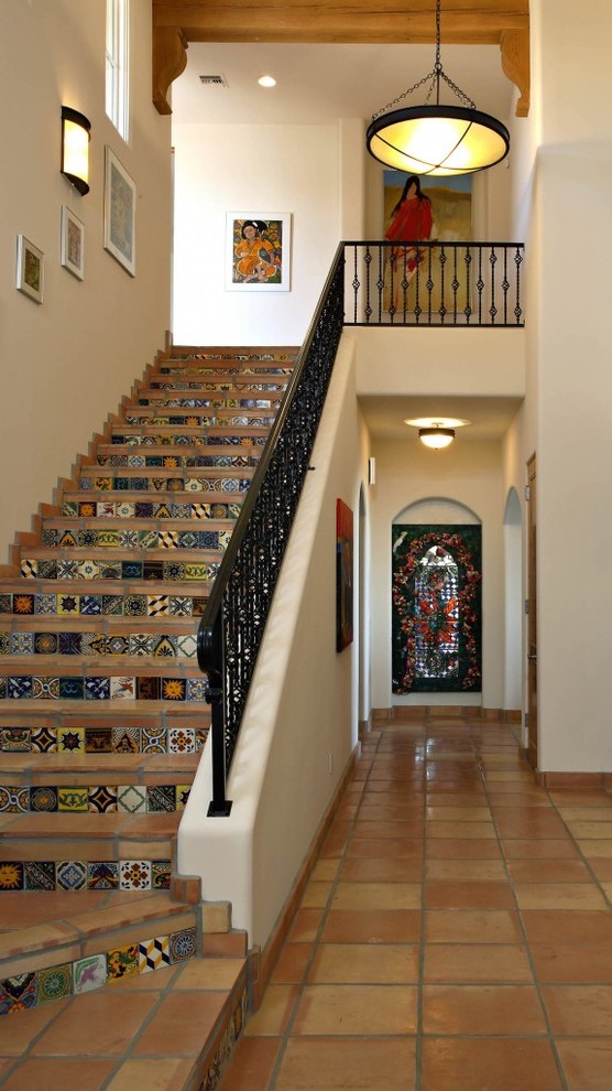 Cette image montre un escalier droit sud-ouest américain avec des marches en terre cuite, des contremarches carrelées et un garde-corps en métal.