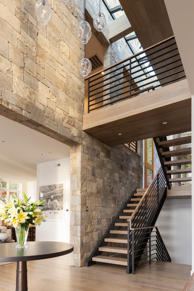 Idée de décoration pour un très grand escalier sans contremarche design en U avec des marches en bois et un garde-corps en métal.