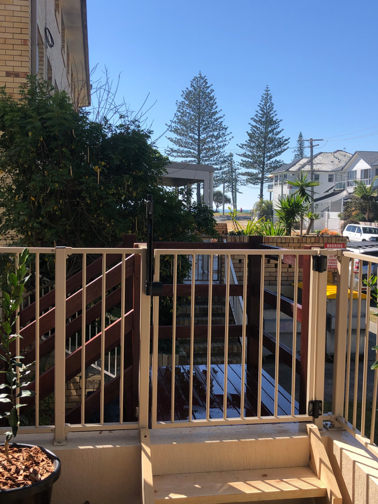 Photo of a small modern wood straight wood railing staircase in Gold Coast - Tweed with open risers and brick walls.