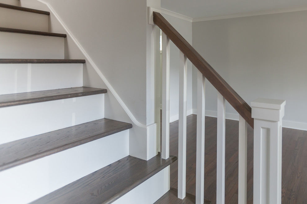 Стильный дизайн: угловая лестница в стиле неоклассика (современная классика) с деревянными ступенями, крашенными деревянными подступенками и деревянными перилами - последний тренд