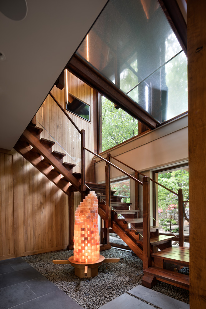 Cette photo montre un escalier sans contremarche rétro en U avec des marches en bois, un garde-corps en verre, palier et éclairage.