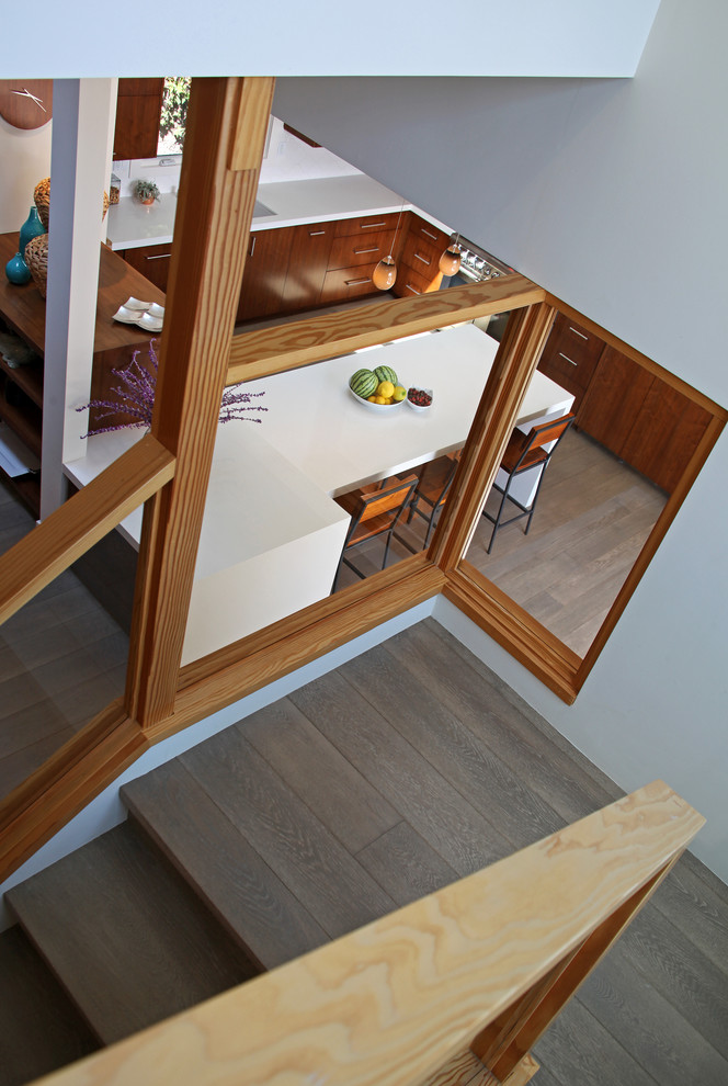 Photo of a medium sized midcentury wood u-shaped glass railing staircase in Orange County with wood risers.