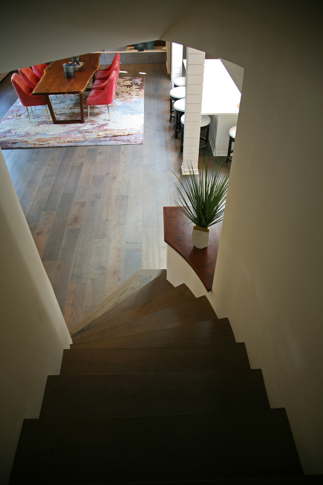 На фото: изогнутая деревянная лестница среднего размера в стиле ретро с деревянными ступенями и перилами из смешанных материалов с