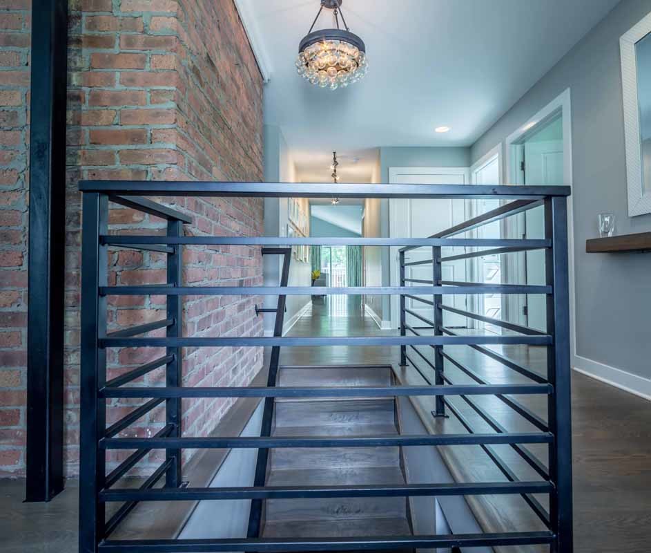 Imagen de escalera recta actual de tamaño medio con escalones de madera, contrahuellas de madera, barandilla de metal y ladrillo