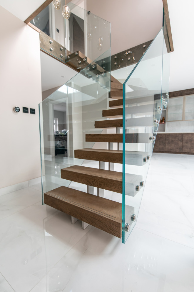 Diseño de escalera en L actual de tamaño medio sin contrahuella con escalones de madera y barandilla de vidrio
