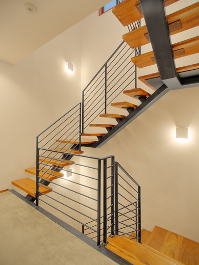 Идея дизайна: огромная изогнутая лестница в стиле модернизм с деревянными ступенями и металлическими перилами без подступенок