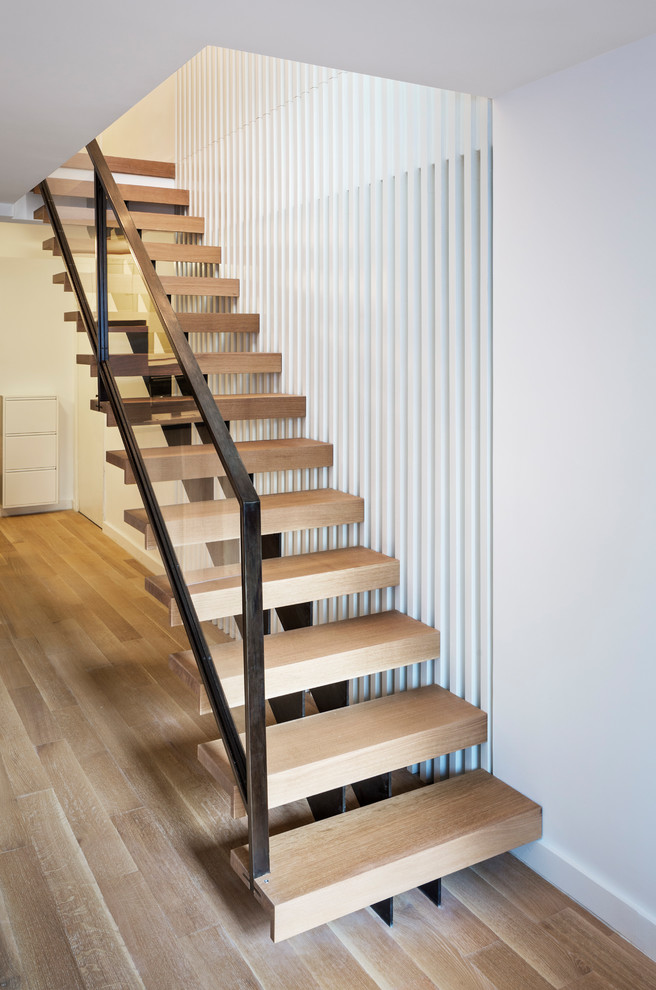 Ejemplo de escalera recta minimalista de tamaño medio sin contrahuella con escalones de madera y barandilla de metal