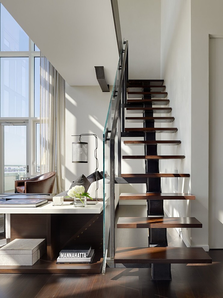 Modelo de escalera recta actual sin contrahuella con escalones de madera y barandilla de vidrio