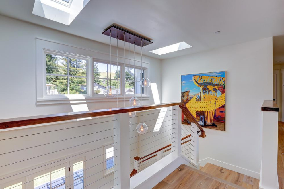 Imagen de escalera en U de estilo de casa de campo grande con escalones de madera, contrahuellas de madera y barandilla de cable