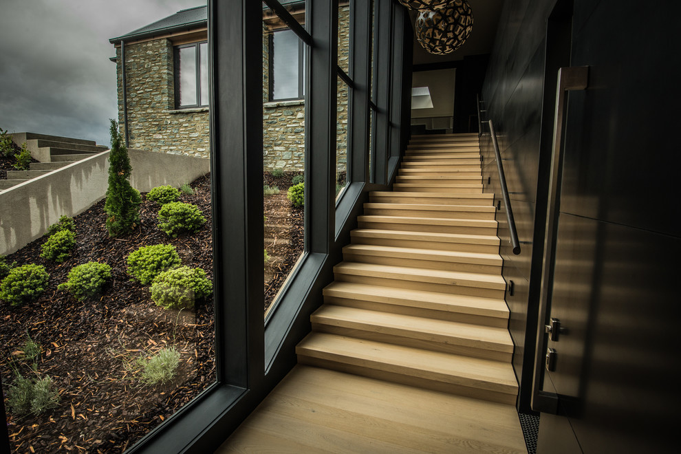 Idée de décoration pour un grand escalier droit minimaliste avec un garde-corps en bois.