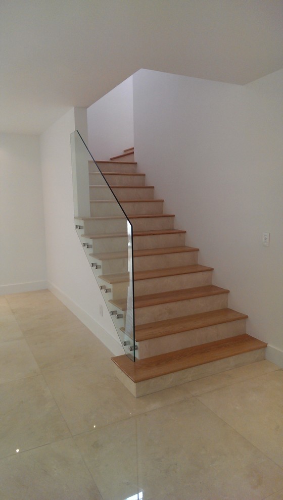 Idée de décoration pour un escalier minimaliste en L de taille moyenne avec des marches en bois, des contremarches carrelées et un garde-corps en verre.