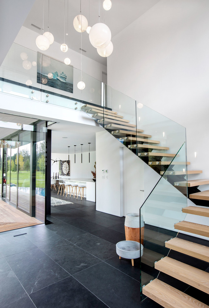 Foto de escalera suspendida contemporánea grande sin contrahuella con escalones de madera y barandilla de vidrio