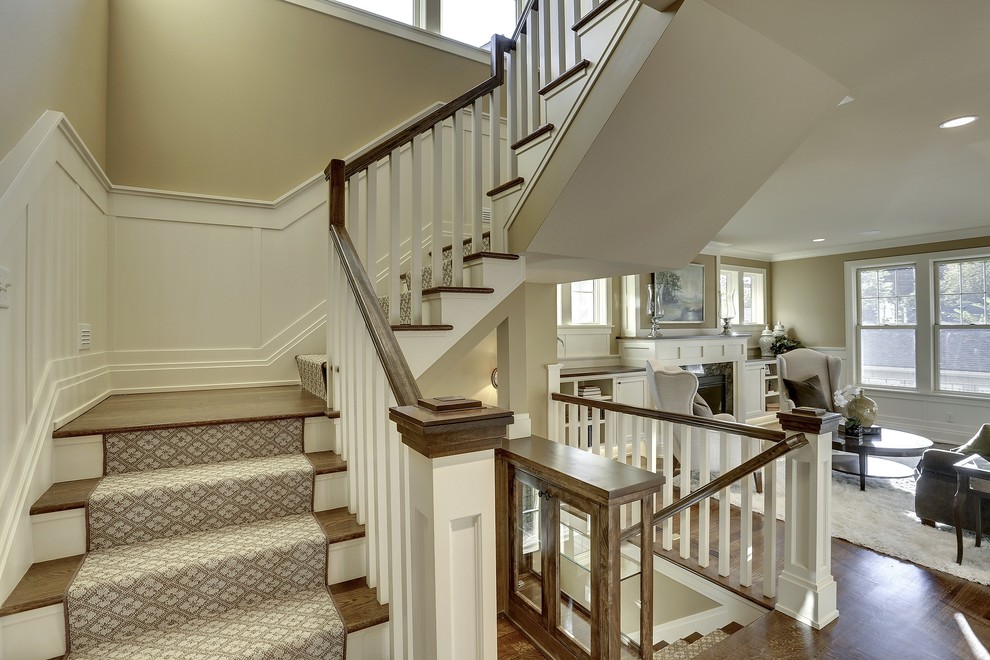 На фото: угловая лестница в стиле неоклассика (современная классика) с ступенями с ковровым покрытием и крашенными деревянными подступенками с