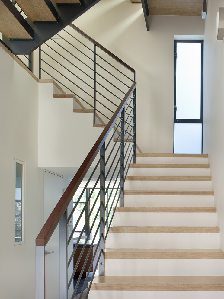 На фото: угловая лестница в современном стиле с деревянными ступенями, крашенными деревянными подступенками и металлическими перилами